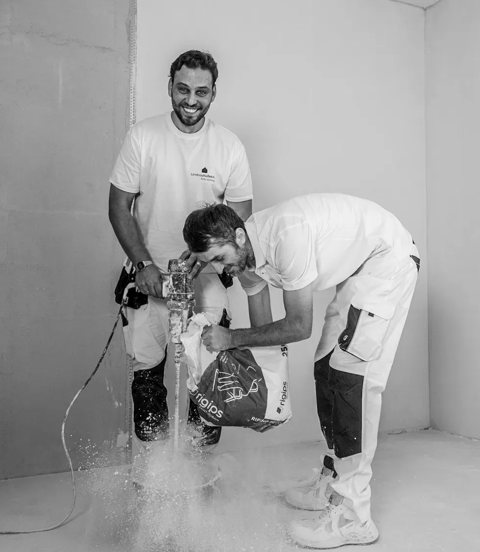 Zwei Handwerker von Umbaukollektiv rühren Material an